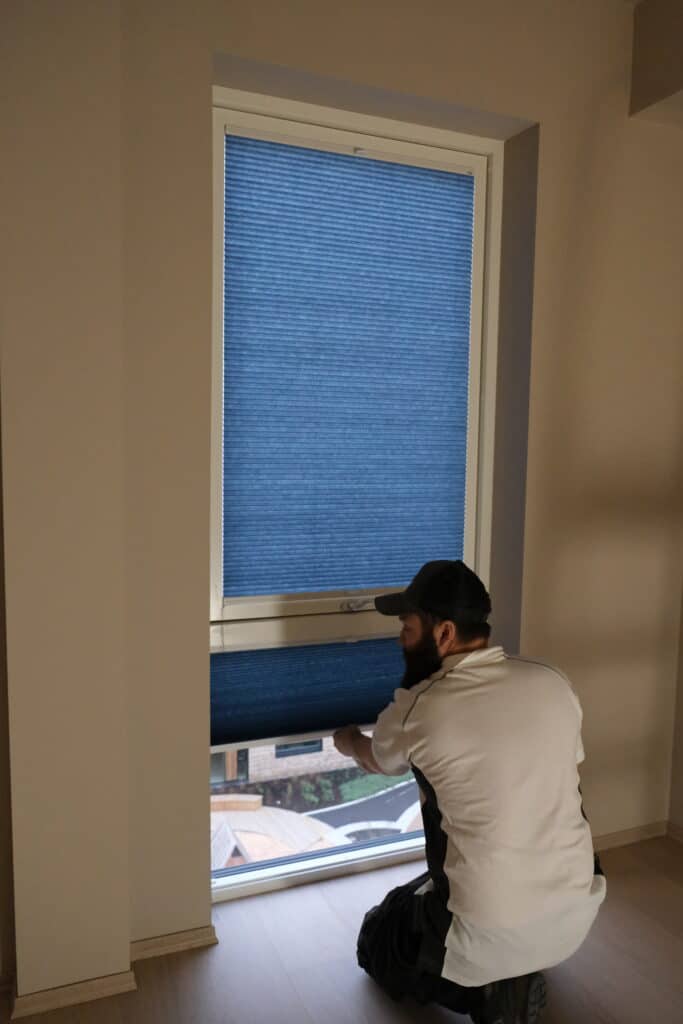 Montør monterer plisségardiner på mål på soverom